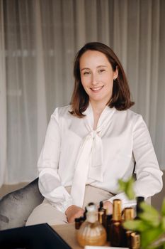 portrait of a smiling girl-woman sitting in an armchair. An aromatherapist in a white blouse is sitting in the office.