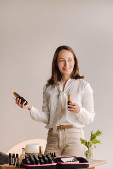 A girl with a white blouse holds bottles of essential oils in her hands.