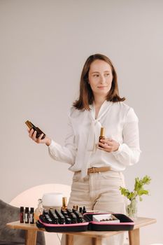 A girl with a white blouse holds bottles of essential oils in her hands.