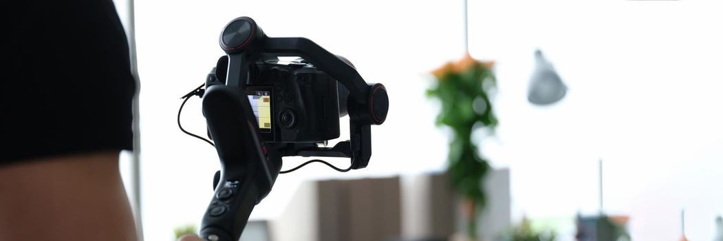 Male photographer with steadicam and camera, close-up, blurry. Professional equipment for photo and video filming, operator