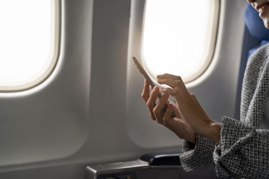 Side view of young businesswoman using smartphone in aircraft, hipster guy holding mobile device for playing or working during flight, business travel concept.