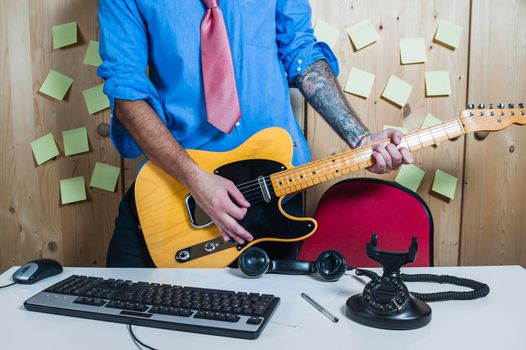 Man playing a guitar in his home office.