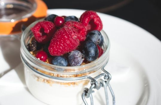 Homemade plain yogurt with granola and fresh fruit in a glass jar