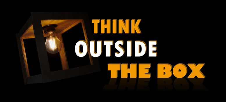 Think outside the box motivational message with a light bulb shining in a wooden box frame