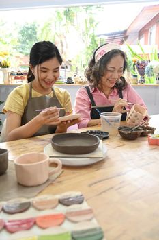 Middle aged woman and young woman making ceramics in craft studio workshop. Activity, handicraft, hobbies concept.