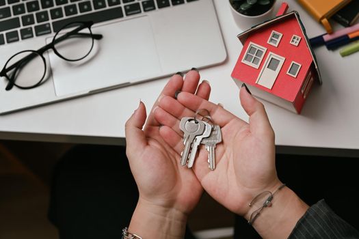 Close up view woman hands holding house keys. Real estate investment and insurance concept.