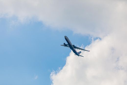 Passenger plane flies in the blue sky with clouds. Aviation industry.