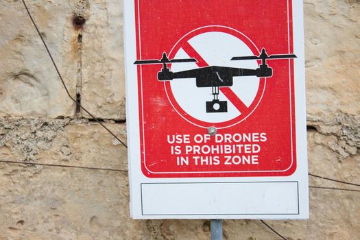 A red sign that reads "Use of drones is prohibited in this zone" against a brick wall