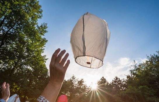 People launching flying lantern during wedding celebration.