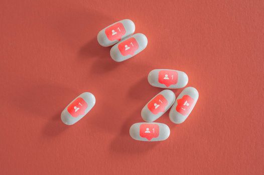 Still life of white pills with social media symbols.