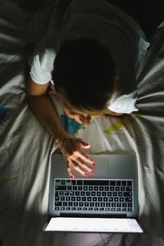 Woman using technolgy at night in the bedroom.