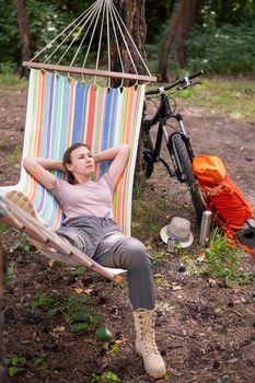 Caucasian woman lies in a hammock in a pine forest.