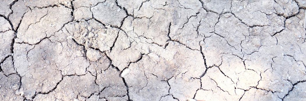 Cracked dry gray earth, close-up of soil erosion. Environmental disaster, drought and crop failure. Environment, hot air