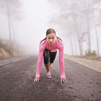 Shot of a young female runner about to start a training session on a misty morning.