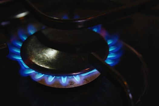 A blue gas flame hob lit up on a domestic kitchen cooker