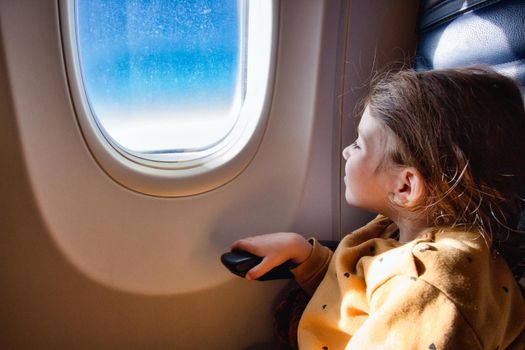 Little girl sat on a commercial flight airplane looking out of the window