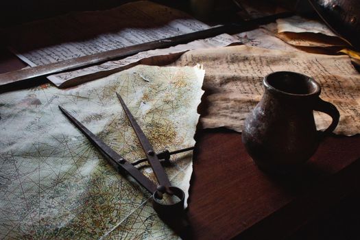 Old metal divider on a map on the captain's table aboard a pirate ship