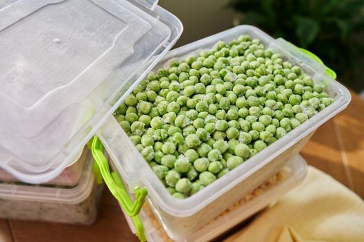 Frozen vegetables and fruits, close-up frozen in the freezer green peas in plastic containers. Seasonal vegetables, food preparations for the winter