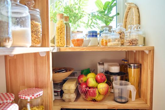 Storage of food in the kitchen in the pantry. Cereals, spices, pasta, nuts, flour in jars and containers, kitchen utensils. Cooking at home, stocking food, household