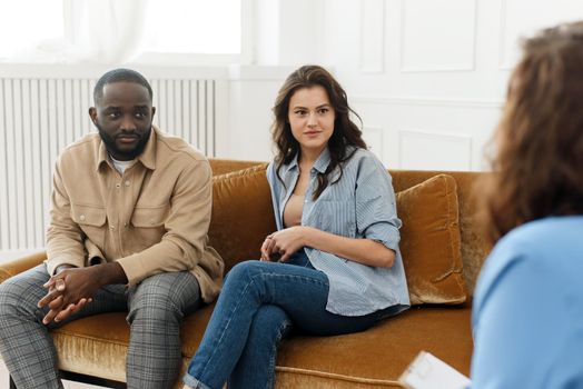 Marriage consulting. Spouses talk to a family psychologist during a meeting after a quarrel, sitting in the office talking about marriage and relationship problems