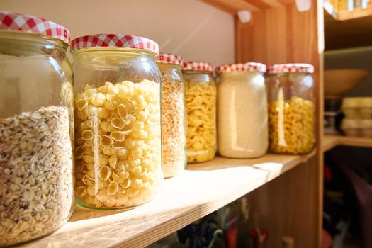 Storage of food in the kitchen in the pantry. Cereals, spices, pasta, nuts, flour in jars and containers, kitchen utensils. Cooking at home, stocking food, household