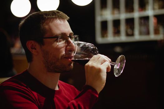 Young man in a restaurant drinking red wine from a glass
