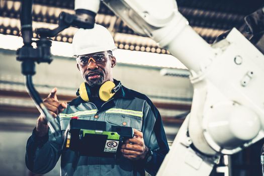 African American factory worker working with adept robotic arm in a workshop . Industry robot programming software for automated manufacturing technology .