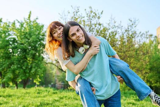 Couple of happy having fun teenagers together outdoor. Young teenage male and female laughing in park on lawn. Joy, happiness, friendship, summer, students, holidays, youth concept