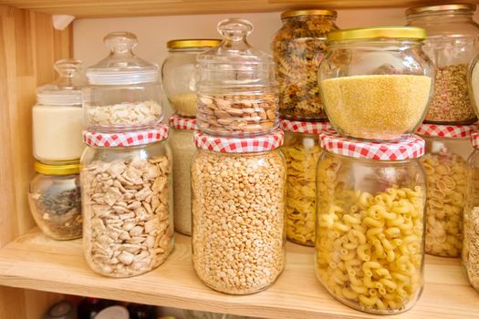 Storage of food in the kitchen in the pantry. Cereals, spices, pasta, nuts, flour in jars and containers, kitchen utensils. Cooking at home, stocking food, household