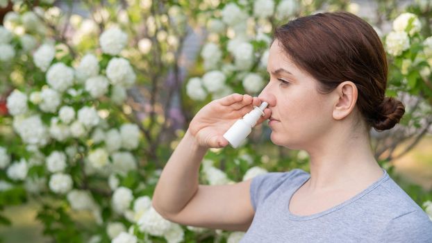 Caucasian woman uses a nasal spray while walking in the park