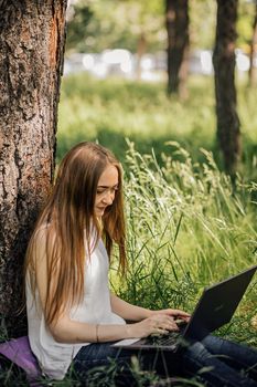 Young business woman working at the computer in cafe on the rock. Young girl downshifter working at a laptop at sunset or sunrise on the top of the mountain to the sea, working day