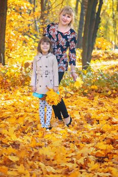 Daughter with mom in the autumn park. Selective focus.