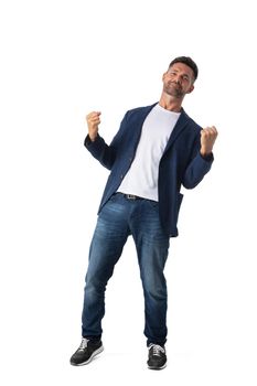 Confident mid adult businessman wearing blazer and jeans holding fists in air standing on white studio background