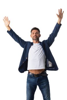 Confident mid adult businessman wearing blazer and jeans with arms raised in air standing on white studio background