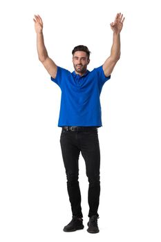 Full length portrait of a man in jeans and blue t-shirt gesturing happiness with raised arms isolated on white background