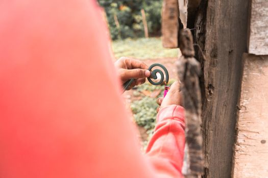 Latino man lighting a mosquito coil outside a house in rural Nicaragua