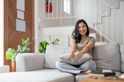 Portrait of smiling happy cheerful beautiful pretty asian woman relaxing on cozy sofa.