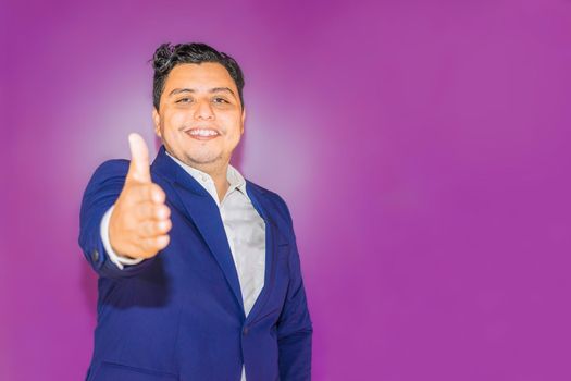 Nicaraguan man with blue suit on purple background with thumb up looking at camera