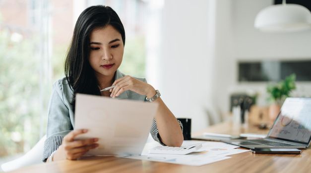 Business woman using calculator for do math finance on wooden desk in office and business working background, tax, accounting, statistics and analytic research concept.