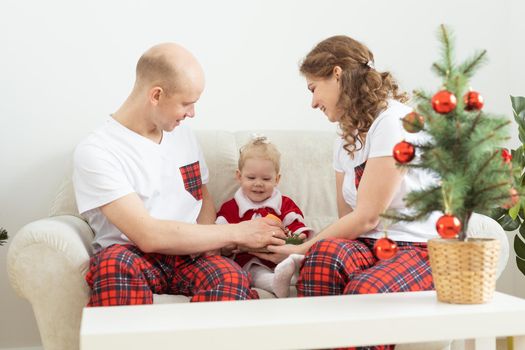 Baby child with hearing aid and cochlear implant having fun with parents in christmas room. Deaf and health