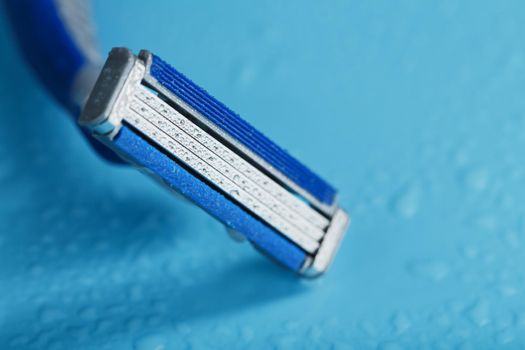 Shaving machine with three blades on a blue background close-up free space