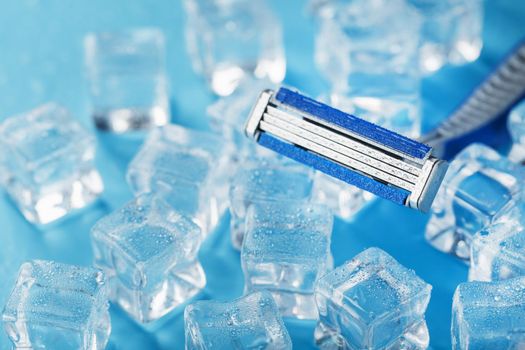 Shaving machine on a blue background with ice cubes. The concept of cleanliness and frosty freshness