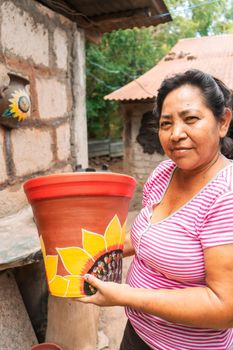 Vertical photo of an artisan from La Paz Centro, Leon, Nicaragua showing a clay pot