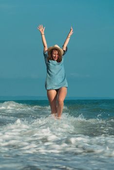 the beautiful girl in a swimsuit in summer on the seashore happily having fun on the water with emotions