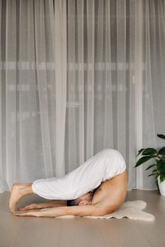 a man with a bare torso does yoga in a fitness room. the concept of a healthy lifestyle.