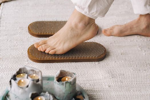 The man's feet are next to boards with nails. Yoga classes.