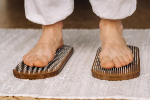 The man's feet are next to boards with nails. Yoga classes.