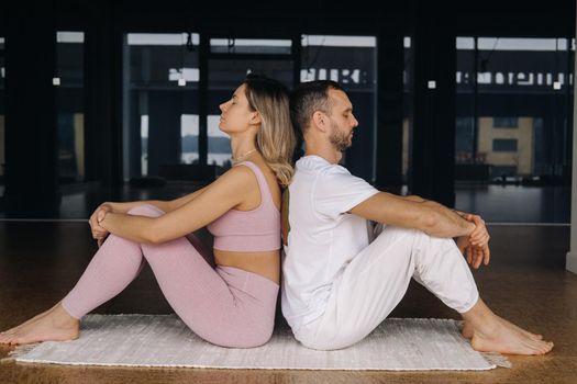 a woman and a man are engaged in pair gymnastics yoga in the gym.