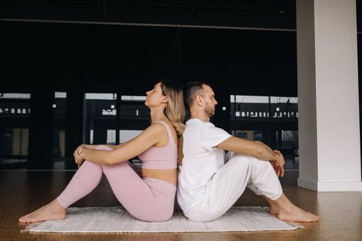 a woman and a man are engaged in pair gymnastics yoga in the gym.