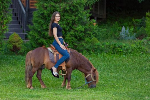 woman riding a pony on the lawn